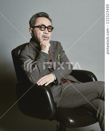 A middle-aged businessman wearing a suit on a gray background 115323489