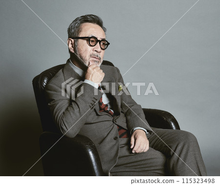 A middle-aged businessman wearing a suit on a gray background 115323498