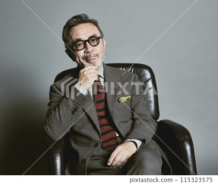 A middle-aged businessman wearing a suit on a gray background A middle-aged businessman wearing a suit on a gray background 115323575