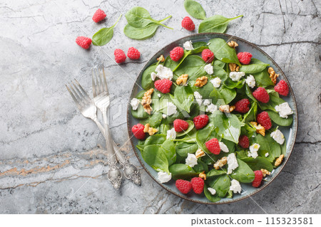 Baby spinach with raspberries, feta and walnuts close-up in a plate. Horizontal top view 115323581