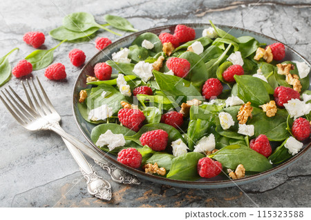 Dietary raspberry spinach salad with feta and walnuts with vinaigrette dressing close-up in a plate. Horizontal Dietary raspberry spinach salad with feta and walnuts with vinaigrette dressing close-up in a plate. Horizontal 115323588