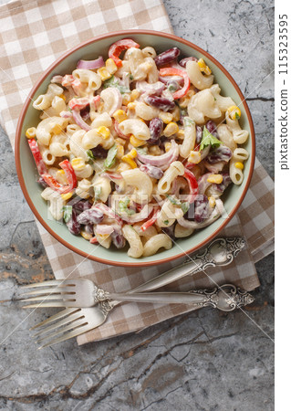Southwestern elbow pasta salad with grilled corn, onion, beans, peppers with creamy dressing closeup on the bowl. Vertical top view Southwestern elbow pasta salad with grilled corn, onion, beans, peppers with creamy dressing closeup on the bowl. Vertical top view 115323595