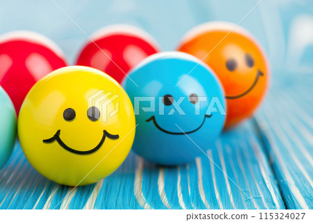 Brightly colored balls with smiley faces on a blue wooden surface 115324027