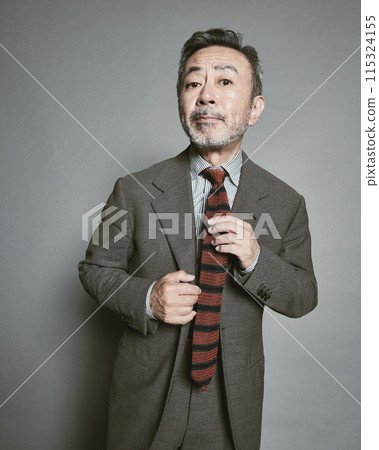 A middle-aged businessman wearing a suit on a gray background A middle-aged businessman wearing a suit on a gray background 115324155