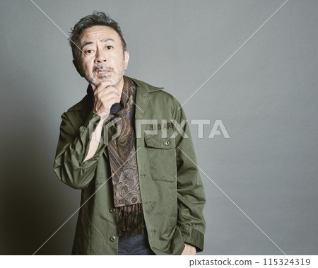 Portrait of a middle-aged man in casual clothes against a gray background 115324319
