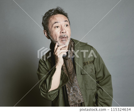 Portrait of a middle-aged man in casual clothes against a gray background 115324634