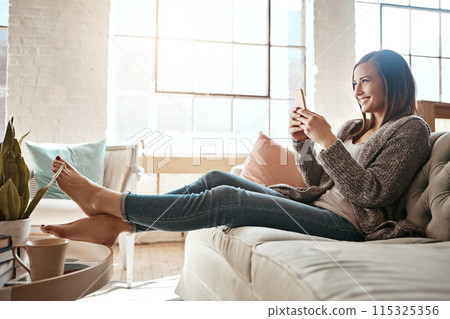 Woman, smile and relax with smartphone on sofa at home for text message, communication and notification. Happy, person and thinking with tech in living room for internet, connection and social media 115325356