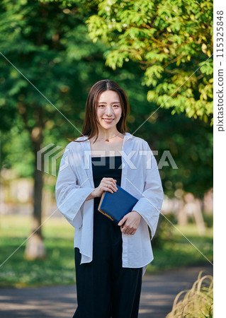A young woman walking with a notebook A young woman walking with a notebook 115325848