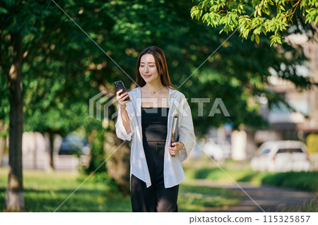 一個操作智能手機的年輕女子 一個操作智能手機的年輕女子 115325857