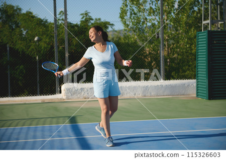 Woman in her 40s playing tennis on a sunny outdoor court Woman in her 40s playing tennis on a sunny outdoor court 115326603