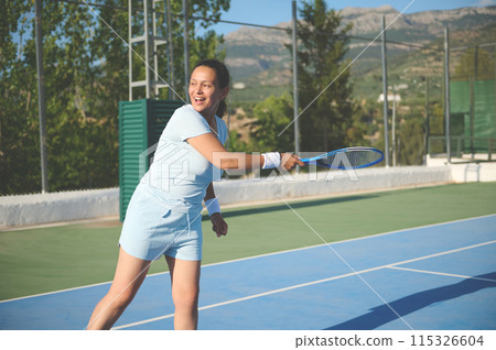 Woman in her 40s playing tennis on a sunny outdoor court Woman in her 40s playing tennis on a sunny outdoor court 115326604