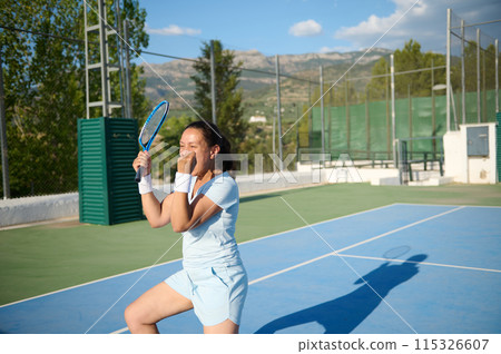Woman in her 40s celebrating on a tennis court, enjoying a victorious moment 115326607