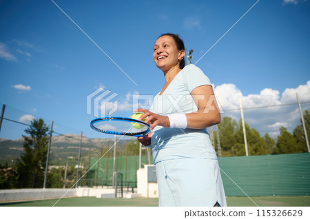 Woman in her 40s playing tennis on outdoor court on a sunny day 115326629