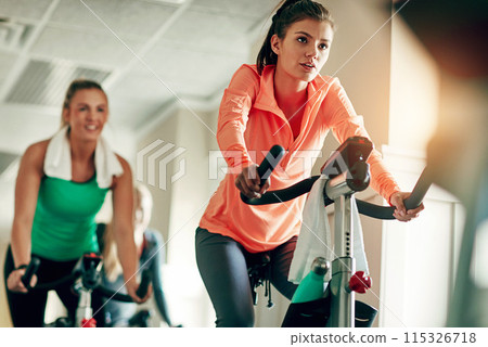 Woman, cycling and workout with spin class at gym for cardio exercise or indoor training together. Active female person or group of cyclists riding on equipment or bicycle for fitness at health club 115326718