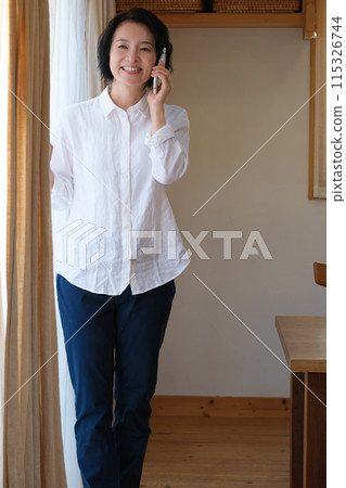 A middle-aged woman calling her family in the living room A middle-aged woman calling her family in the living room 115326744