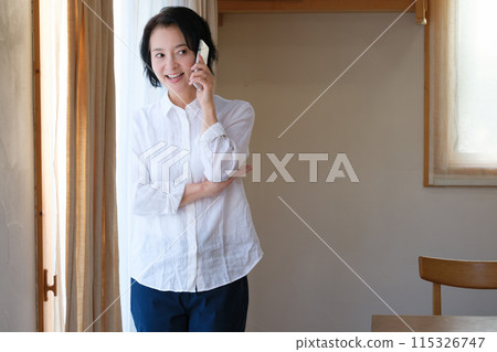 中年婦女在客廳打電話給家人 中年婦女在客廳打電話給家人 115326747