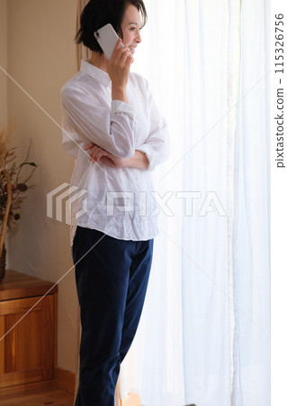 中年婦女在客廳打電話給家人 中年婦女在客廳打電話給家人 115326756