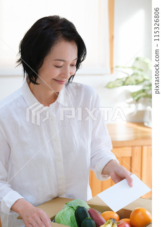 中年婦女將一封信放入紙箱以獲得零用錢 中年婦女將一封信放入紙箱以獲得零用錢 115326806