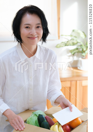 A middle-aged woman putting a letter into a cardboard box for remittance 115326810