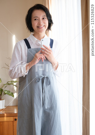 在客廳裡操作智能手機的中年女人 在客廳裡操作智能手機的中年女人 115326829