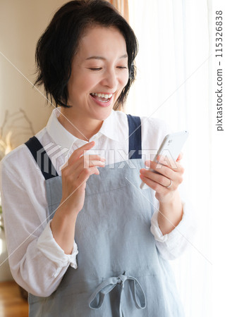 A middle woman who operates a smartphone in the living room A middle woman who operates a smartphone in the living room 115326838