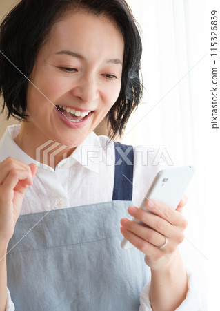 A middle woman who operates a smartphone in the living room A middle woman who operates a smartphone in the living room 115326839