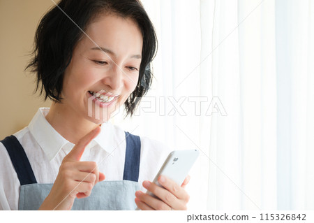 在客廳裡操作智能手機的中年女人 在客廳裡操作智能手機的中年女人 115326842