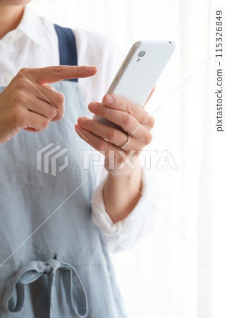 在客廳裡操作智能手機的中年女人 在客廳裡操作智能手機的中年女人 115326849