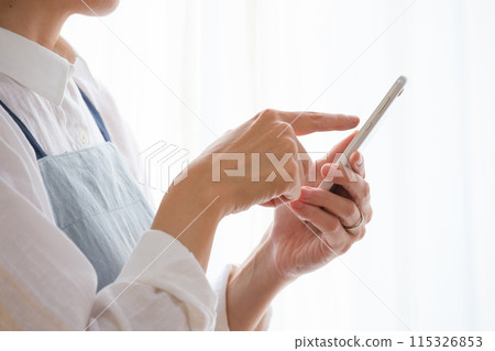 在客廳裡操作智能手機的中年女人 在客廳裡操作智能手機的中年女人 115326853