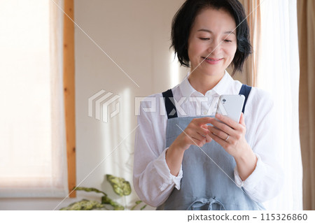 在客廳裡操作智能手機的中年女人 在客廳裡操作智能手機的中年女人 115326860