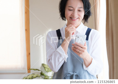 A middle woman who operates a smartphone in the living room 115326865