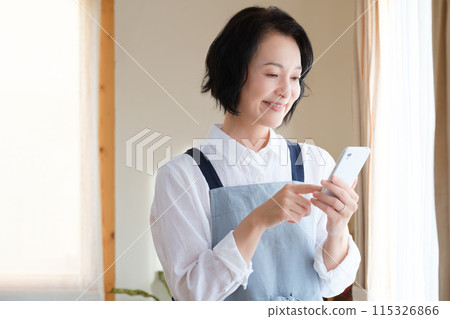 A middle woman who operates a smartphone in the living room A middle woman who operates a smartphone in the living room 115326866