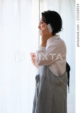 A middle-aged woman calling her family in the living room 115326914