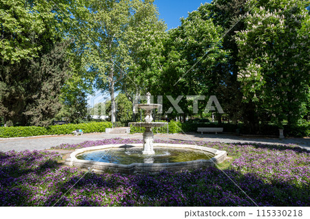 Lovely fountain amidst flowers in El Retiro Park in Madrid, Spain on sunny day. 115330218