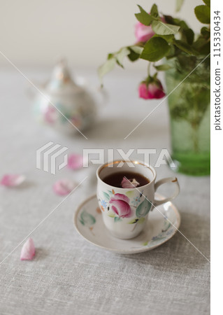 Moody summer still life. Table composition with cup of coffee, tea and beautiful floral bouquet with pink roses 115330434