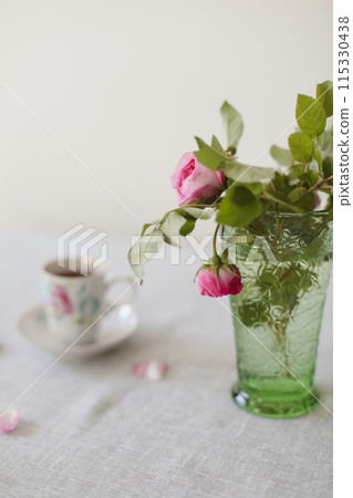 Moody summer still life. Table composition with cup of coffee, tea and beautiful floral bouquet with pink roses 115330438