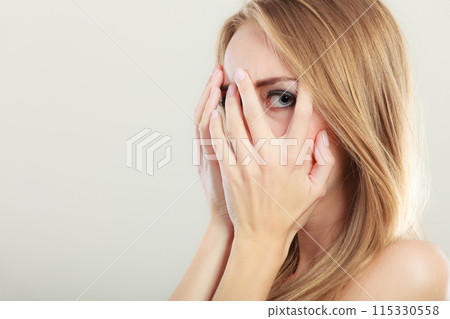 Afraid frightened woman peeking through her fingers Afraid frightened woman peeking through her fingers 115330558