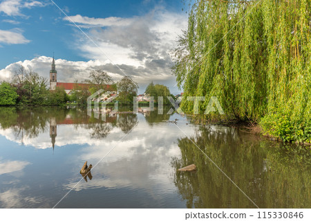 Huttenheim village reflected in a natural tree-lined river in spring. Huttenheim village reflected in a natural tree-lined river in spring. 115330846