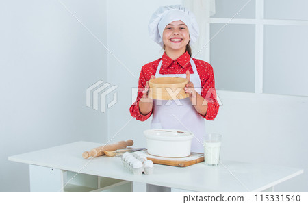 nice day. professional and skilled baker. kid in chef uniform and hat. teen girl preparing dough. making cake by recipe. time to eat. happy child cooking in kitchen. bake cookies in kitchen 115331540