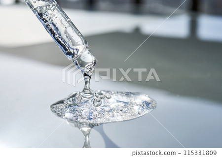 Pipette with serum shimmering in the sun on a blue background. Pipette with serum shimmering in the sun on a blue background. 115331809