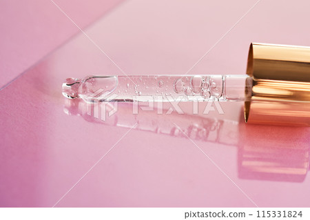 Pipette with serum shimmering in the sun on a pink background. 115331824