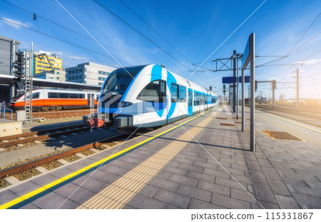 High-speed blue passenger train at railway station at sunset 115331867