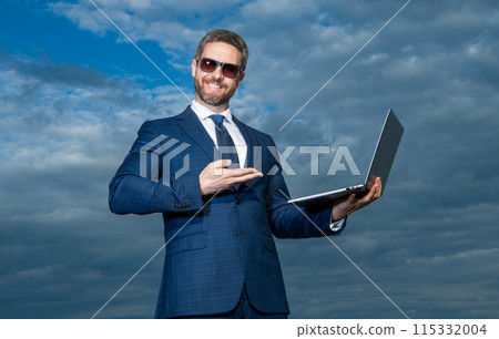 Happy QA engineer presenting product pointing at laptop. QA professional making presenting gesture Happy QA engineer presenting product pointing at laptop. QA professional making presenting gesture 115332004