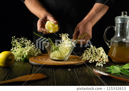 Adding lemon manually to a glass container with elderberries before making a cold drink or kvass. The concept of making a medicinal drink based on folk recipes Adding lemon manually to a glass container with elderberries before making a cold drink or kvass. The concept of making a medicinal drink based on folk recipes 115332613