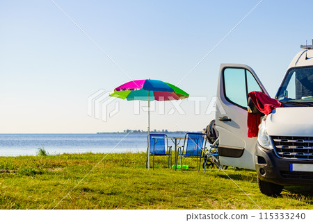 Umbrella with chairs at campervan on beach 115333240