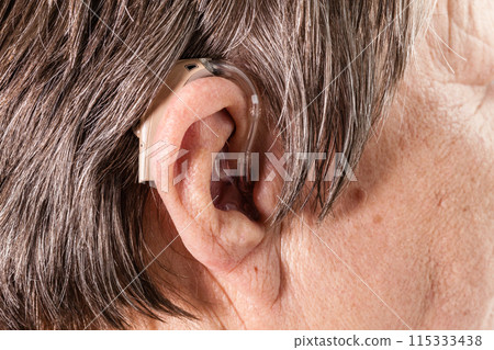 Closeup senior woman using hearing aid 115333438