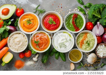 A variety of vegetables and sauces are displayed in bowls on a counter 115333820