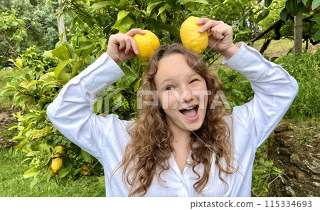 girl teenager have fun dancing smiles and laughs against the backdrop of a lemon tree in her hands she has lemons she fools around with them girl teenager have fun dancing smiles and laughs against the backdrop of a lemon tree in her hands she has lemons she fools around with them 115334693