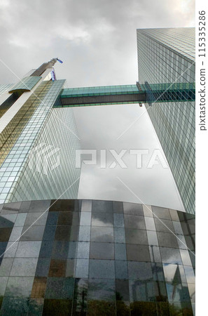 Glass skyscrapers with sky bridge and reflective surfaces stand out in cityscape 115335286