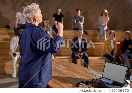 Female speaker giving presentation in hall in university. group of young people in audience 115336570